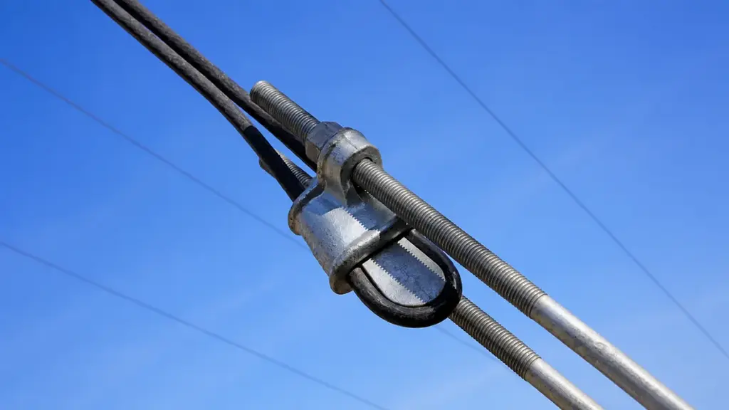 Galvanized wire rope clamp and turnbuckle against a clear blue sky