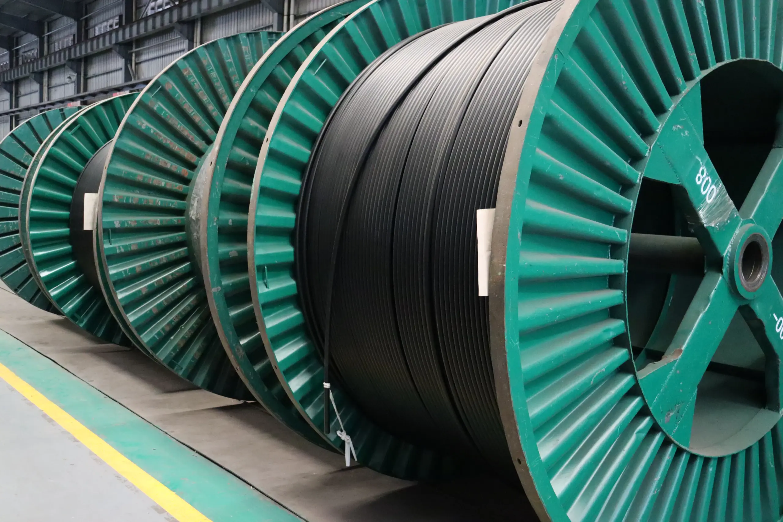 Thick black armored medium-voltage cables coiled on a large wooden drum